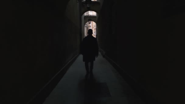 Komea mies kävelee tunnelissa talojen välillä vanhassa kaupungissa. - Materiaali, video