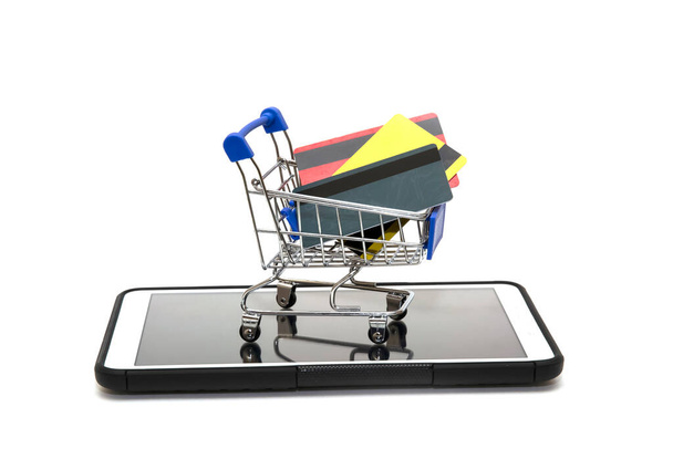 tarjetas bancarias en un pequeño carrito de compras que se encuentra en una tableta. concepto de compras en línea en Internet
. - Foto, Imagen