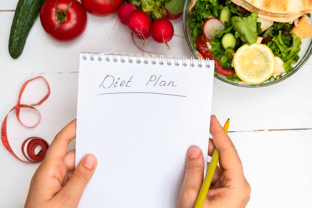 Vue du dessus des mains de la femme tenant un bloc-notes avec des mots manuscrits Diet Plan
 - Photo, image