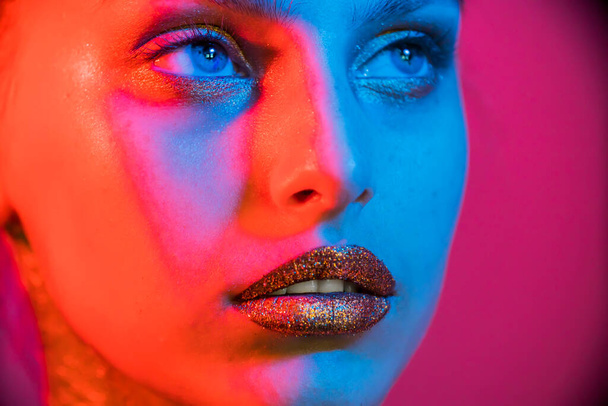 Modella metallica labbra d'argento e viso donna in neon uv luci blu e viola, in posa in studio, bella ragazza, incandescente make-up, trucco colorato
.  - Foto, immagini