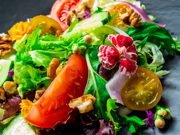 Különböző salátafélék, paradicsom, hagyma, uborka és diófélék salátája. - Fotó, kép