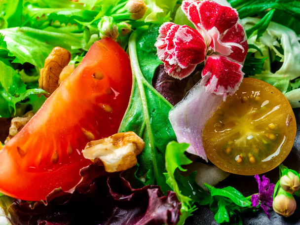 Salade van verschillende soorten sla, tomaat, ui, komkommer en noten. - Foto, afbeelding