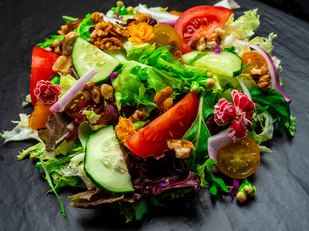 Salad of different types of lettuce, tomato, onion, cucumber and nuts. - Photo, Image