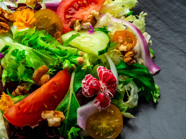 Különböző salátafélék, paradicsom, hagyma, uborka és diófélék salátája. - Fotó, kép