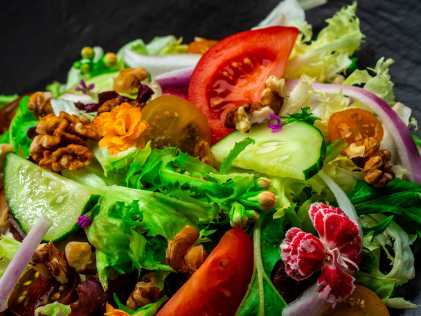 Salade van verschillende soorten sla, tomaat, ui, komkommer en noten. - Foto, afbeelding