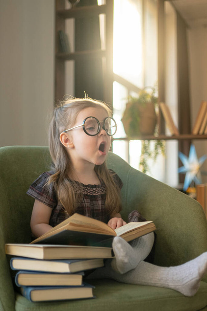 Little cute toddler girl in glasses reading books. back to school - Fotografie, Obrázek