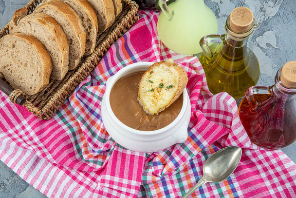 Slavné francouzské jídlo, francouzská cibulová polévka. Karamelizovaná cibule vařená na skladě s vínem a bylinkami, zakončená opečenou bagetou a sýrem a dopečená pod grilem. - Fotografie, Obrázek