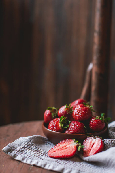 Fresh strawberries in a bowl on wooden table with low key scene. copy space - Foto, Bild