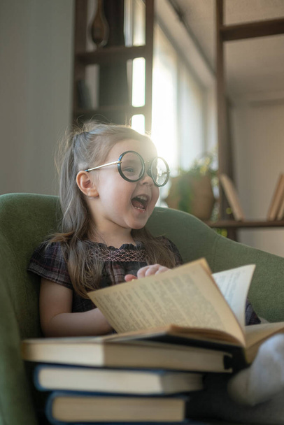 Little cute toddler girl in glasses reading books. back to school - Fotoğraf, Görsel
