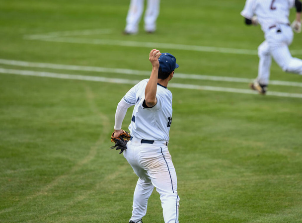 Jogador de beisebol em ação durante um jogo de beisebol
 - Foto, Imagem