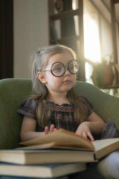 Little cute toddler girl in glasses reading books. back to school - Foto, afbeelding