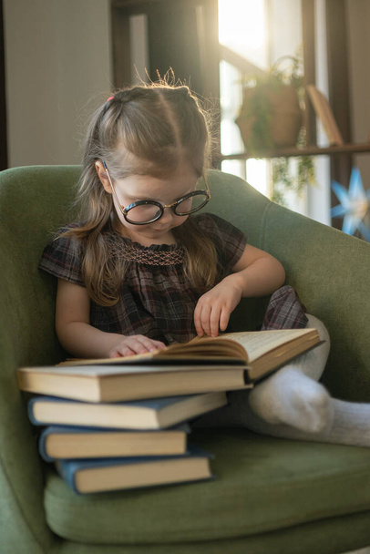 Little cute toddler girl in glasses reading books. back to school - Photo, image