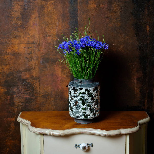 Belles fleurs sauvages d'été bleuets dans un vase sur un fond brun texturé sombre et humide
 - Photo, image