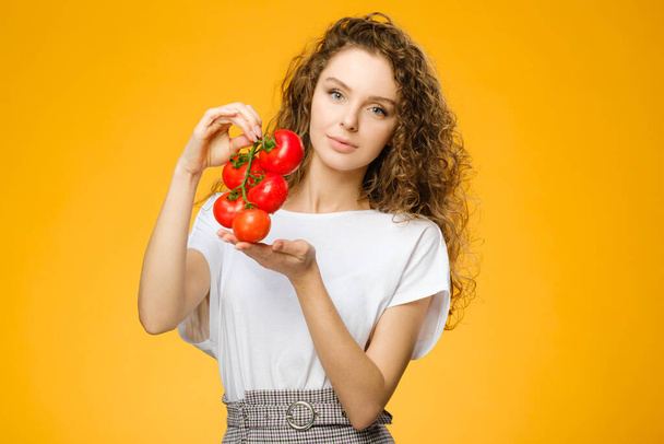 Portrait of pretty caucasian girl with curly hair holding vegetables isolated on colorful yellow background in studio - Foto, Imagem