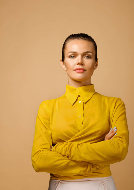 Szoros portré vonzó kaukázusi üzletasszony visel színes sárga ing elszigetelt bézs háttér stúdió - Fotó, kép