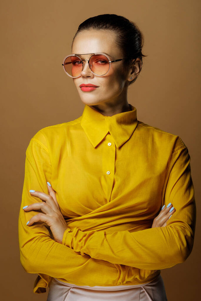 Closeup portrait of attractive caucasian business lady wearing colorful yellow shirt isolated on beige background in studio - Foto, afbeelding