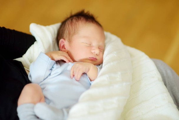 Cute little newborn baby boy sleeping in his mothers arms. Portrait of tiny new baby at home. Adorable son being held by his mommy. New bundle of joy. - Φωτογραφία, εικόνα