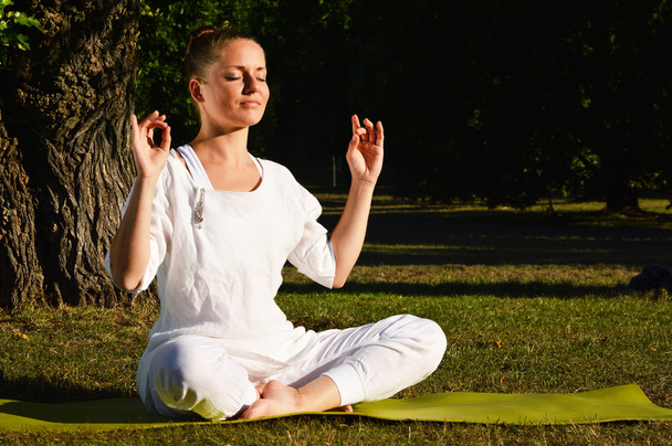 Молодая женщина во время медитации йоги в парке
 - Фото, изображение