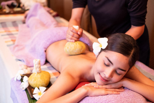 Giovane donna che fa un massaggio con le borse a base di erbe nel salone spa
 - Foto, immagini