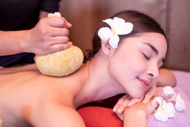 Młoda kobieta mająca masaż torebkami ziołowymi w salonie spa - Zdjęcie, obraz