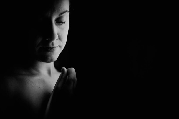 Στοκ φωτογραφία σε μαύρο και άσπρο μιας καυκάσιας ενήλικης γυναίκας σε ένα σκοτεινό απομονωμένο δωμάτιο κρατώντας ένα λευκό πανί. - Φωτογραφία, εικόνα