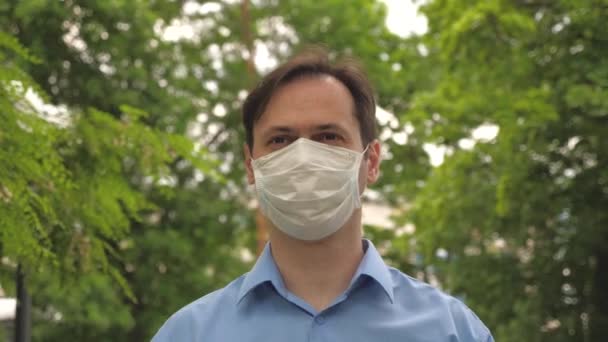 Ga gemaskerd op straat om te winkelen. COVID-19. Een man gaat in de stad werken met een medisch masker op. gezichtsscherm op jongeman buiten in het park. mens toerist beschermen gezicht tegen virussen. - Video