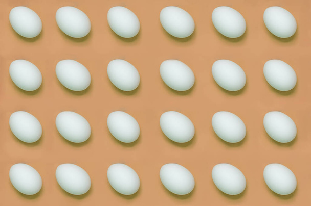 Beyaz yumurtalar düzgün bir şekilde kahverengi arka planda dizilmiş.. - Fotoğraf, Görsel
