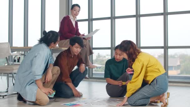 Grupo de jóvenes creativos de Asia en ropa casual discutiendo ideas de reuniones de tormenta de ideas de negocios plan de proyecto de diseño de software de aplicación móvil presentado en el piso en la oficina. Concepto de trabajo en equipo. - Metraje, vídeo