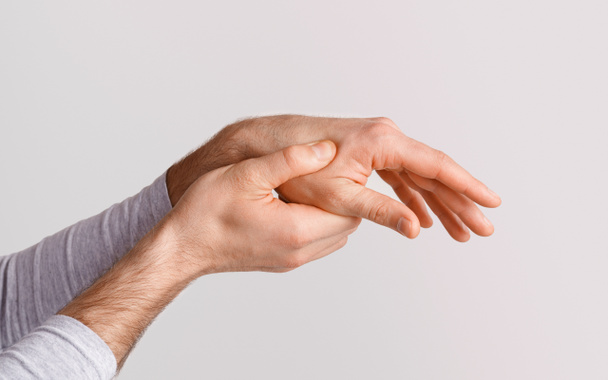 Κάταγμα, τραυματισμό ή πόνος στο χέρι. Ο άνθρωπος πιέζει το ένα χέρι με το άλλο - Φωτογραφία, εικόνα