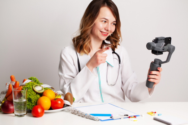 Eine junge Diätassistentin im Beratungszimmer schreibt einen Blog über Gewichtsverlust und gesunde Ernährung - Foto, Bild