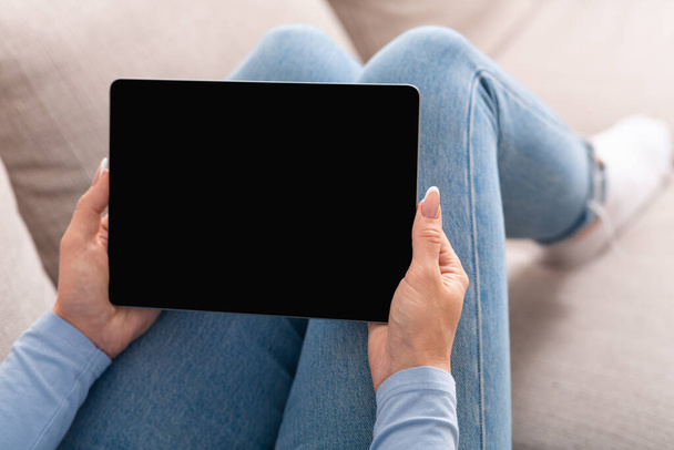 Videoanrufe und intelligente Technologie. Frau hält Tablet in Händen auf Sofa - Foto, Bild