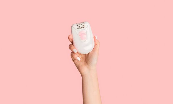 Unrecognizable millennial girl showing modern electric epilator on pink background - Photo, Image