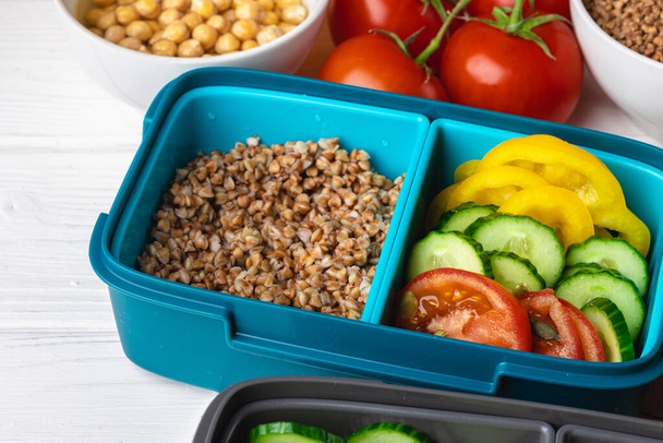 Lunch box with cooked buckwheat and fresh vegetable salad - Foto, afbeelding