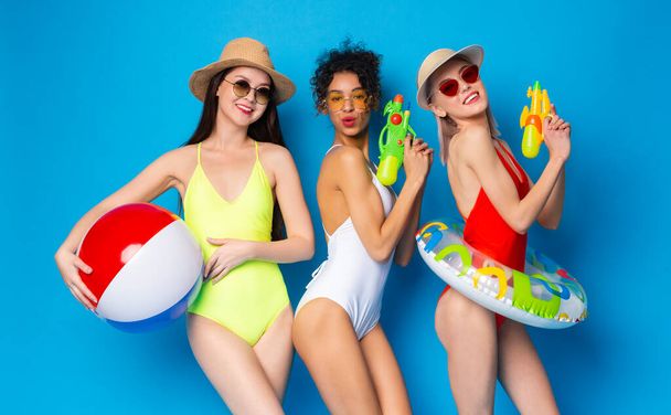 Giovani ragazze in costume da bagno divertirsi con i giocattoli di nuoto su sfondo blu
 - Foto, immagini