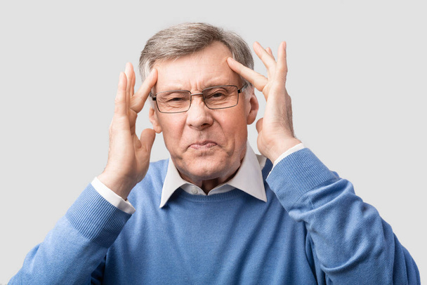 Старший трогательный мужчина с головной болью позирует на сером фоне
 - Фото, изображение