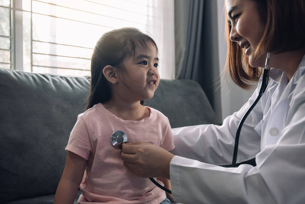 Sebevědomý asijské žena zdravotnický pracovník návštěva její pacient pomocí stetoskop během mladé ženy pacienta dobře zkontrolovat doma. - Fotografie, Obrázek