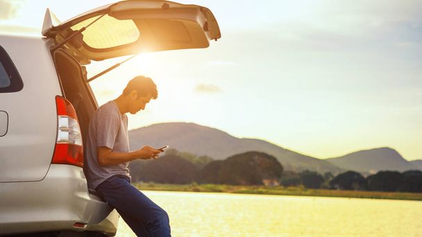 Силуэт мужчины, стоящего рядом с машиной и смотрящего на закат
 - Фото, изображение