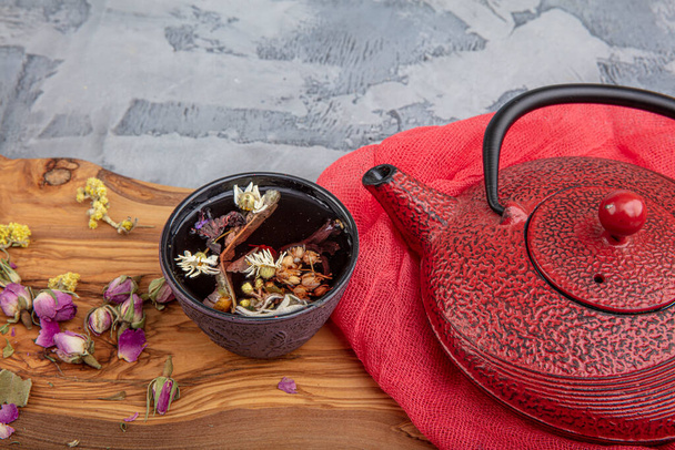 Stillleben mit traditionellem asiatischen Kräutertee, zubereitet in einer alten gusseisernen Teekanne mit trockenen Bio-Kräutern auf einem rustikalen Holztisch. Retro-Filter. - Foto, Bild