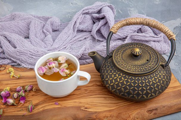 Stillleben mit traditionellem asiatischen Kräutertee, zubereitet in einer alten gusseisernen Teekanne mit trockenen Bio-Kräutern auf einem rustikalen Holztisch. Retro-Filter. - Foto, Bild