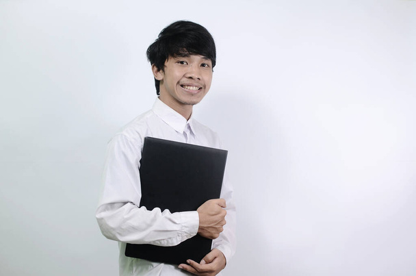 Młodzi Azjaci noszą białe koszule i torby na białym tle. mężczyzna przytula swojego laptopa - Zdjęcie, obraz