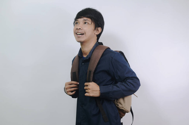 Mladý muž s veselým výrazem. Mladí asijští muži nosí modré košile a tašky izolované na bílém pozadí - Fotografie, Obrázek