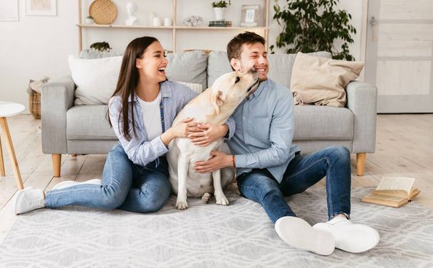 Young happy couple sitting on floor with their labrador - Photo, Image