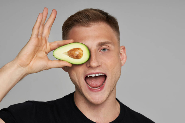 Avocado Facial Treatment. Skin Care With Natural Vitamins. Male Model Holds Fresh Fruit Near Face And Screams. - 写真・画像