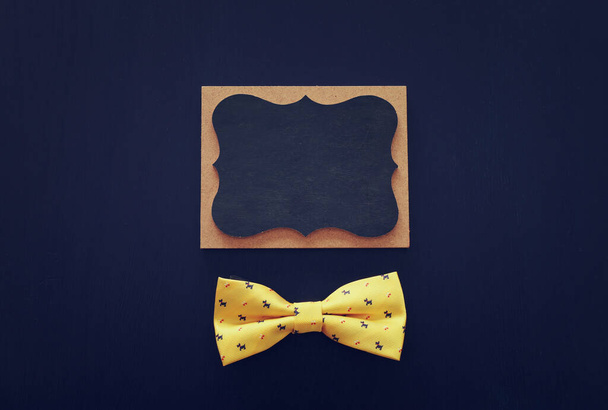 Father's day concept. Bow tie and empty blackboard over dark blue background. top view, flat lay - Foto, afbeelding