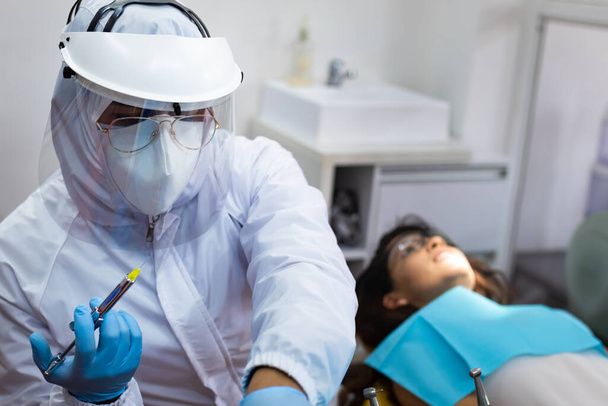 Zahnarzt bereitet Oralanästhesie für junge Patientin vor - Foto, Bild