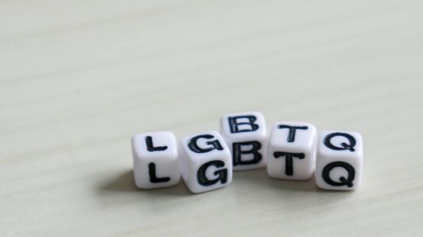 LGBTQのアルファベットの白い立方体。柔らかい木の背景にアルファベットの白い立方体. - 写真・画像
