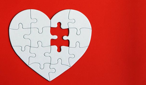 Puzzle de coeur sur le fond rouge. Une pièce manquante du puzzle cardiaque. - Photo, image