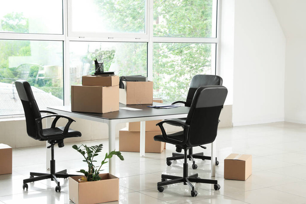 Boîtes en carton avec effets personnels et mobilier dans un nouveau bureau le jour du déménagement
 - Photo, image