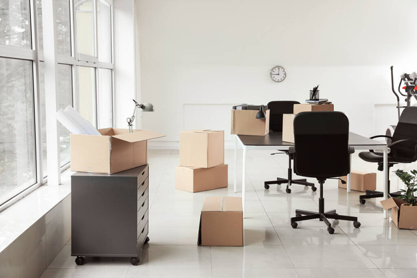 Cardboard boxes with belongings and furniture in new office on moving day - Foto, Bild