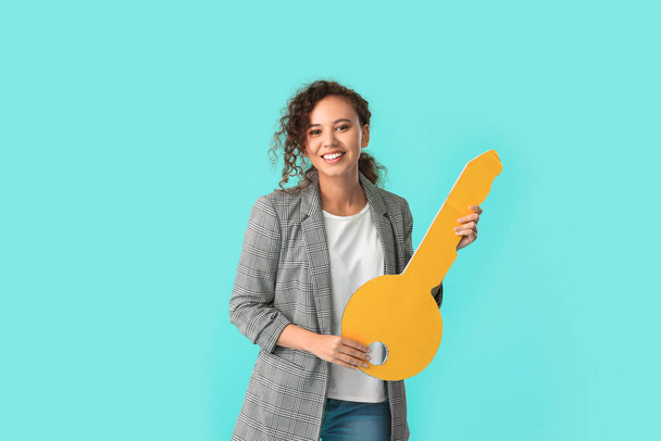 Happy young woman with big paper key on color background - Fotografie, Obrázek